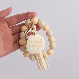 Porte-clés bracelet en perles de silicone avec disque en bois et détail de gland.