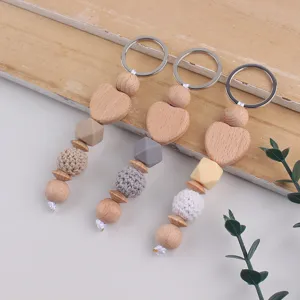 Handmade beech wood heart and yarn bead keychain charm, creative bag accessory detail.