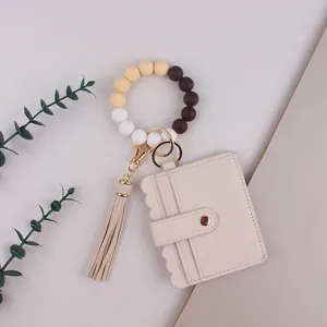 Détail de porte-clés bracelet en perles de silicone avec porte-carte en cuir PU et gland.