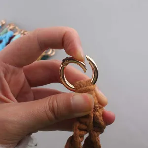 Dettaglio portachiavi in macramè fatto a mano con chiusura a molla dorata e corda di cotone marrone.