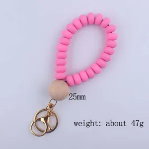 Silicone bead wristlet keychain detail, pink flat beads with wooden ball and metal rings.