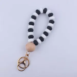Close-up detail of black and white silicone bead keychain with natural wood bead and gold ring.