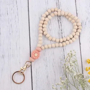 Nahaufnahme der Holzperlen Schlüsselanhänger mit rosa Silikon Gänseblümchen Anhänger.