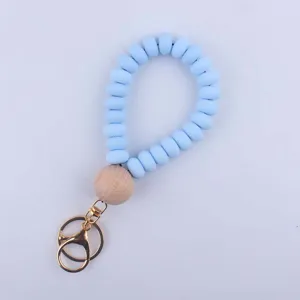 Silicone beaded keychain detail, light blue flat beads with large wooden bead and gold hardware.