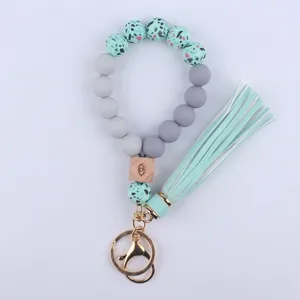 Detailed view of silicone bead wristlet keychain with tassel and wooden eye charm pendant.
