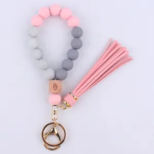Detail view of silicone bead wristlet keychain with wooden charm and pink tassel pendant.