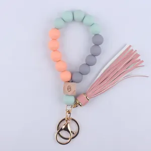 Silicone beaded wristlet keychain with wooden eye bead, leather tassel and gold metal ring.