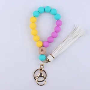 Silicone bead wristlet keychain with wooden eye cube and white tassel for daily use.
