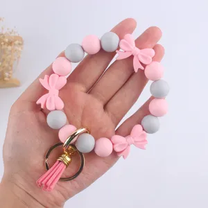 Dettaglio braccialetto portachiavi in perline di silicone con perline grigio rosa.