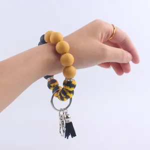 Porte-clés bracelet élégant en perles de silicone avec motif tournesol et gland en cuir noir.