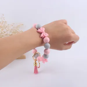 Bracciale portachiavi in perline di silicone con fiocchi rosa e nappa al polso.