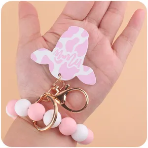 Silicone bead keychain wristlet with pink cow pattern pendant and metal hardware detail.