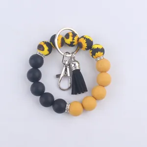 Porte-clés bracelet en perles de silicone avec motif tournesol et pompon en cuir noir.