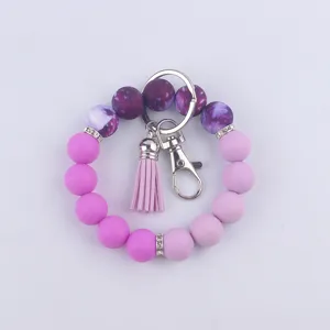 Porte-clés bracelet en perles de silicone avec pompon en cuir et fermoir métal chic.