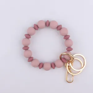 Llavero de pulsera de cuentas de silicona con herrajes metálicos dorados, detalle elegante.