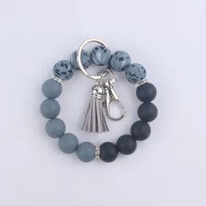 Détail de porte-clés bracelet en perles de silicone avec dégradé gris et gland en cuir.