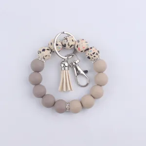 Porte-clés bracelet en perles de silicone avec pompon en cuir et anneau en métal pour clés.