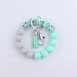 Porte-clés bracelet en perles de silicone avec pompon et fermoir métallique pour usage quotidien.