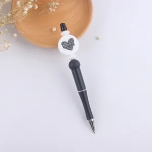 Close-up detail of DIY beadable ballpoint pen showing black body and silicone heart bead decoration.