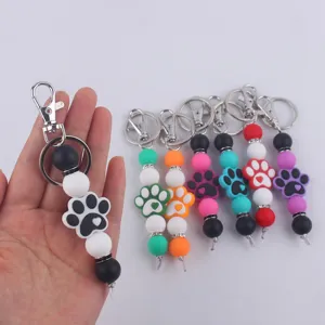 Detalle de llavero de huella de silicona con cuentas de colores y cierre de metal.