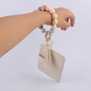 Llavero de pulsera de cuentas de silicona con tarjetero de cuero PU y detalle de borla.