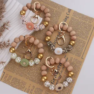Silikon Gänseblümchen Perlen Schlüsselarmband Detail mit Holzteilen und goldenem Karabiner.