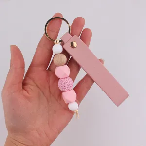 Dettaglio portachiavi in pelle rosa con perline in silicone e legno ed anello in metallo dorato.