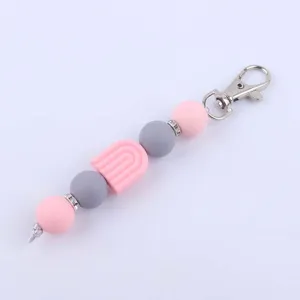 Detailed view of silicone beaded keychain with pink and grey beads and cute rainbow arch charm.