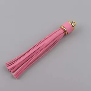 Dettaglio nappa in pelle rosa, cappuccio in metallo dorato, accessorio bracciale gioiello.