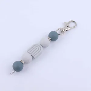 Silicone beaded keychain detail view, featuring contrast grey beads and rainbow charm.
