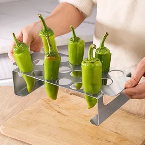Edelstahl-Pfeffer-Grillgestell mit frischen grünen Chilis über einem Holzbrett.