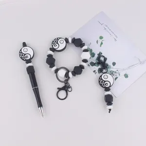 Gedetailleerde set van zwart-witte yin-yang zon ster kralenpen, siliconen armband en sleutelhanger.