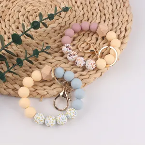 Silicone bead wristlet keychain with wooden accents and floral print design, stylish and practical.