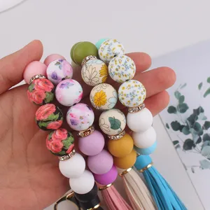 Primer plano de llaveros de cuentas de silicona de colores con estampado floral y borlas.