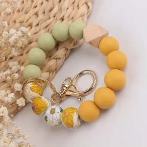 Silicone bead wrist keychain with beech wood and floral patterns, detailed view, stylish strap.