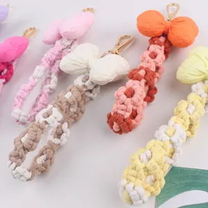 Handmade woven wristlet keychain with plush bow and floral macrame design phone charm.