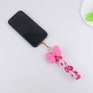 Detail view of the pink woven phone charm with stuffed bow and cute daisy flowers.