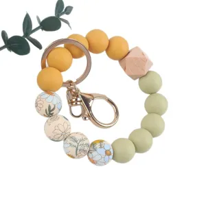 Silicone bead wristlet keychain with wooden bead and floral pattern, portable key ring strap.