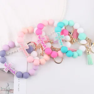 Detailed view of silicone beaded bracelet keychains with cross charms and cute tassel designs.