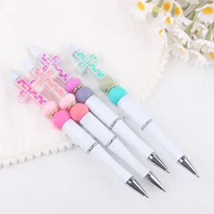 Close-up detail of DIY beaded ballpoint pens featuring colorful cross toppers and silicone beads.