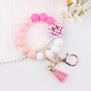 Cute silicone bead wristlet keychain with smiley face pendant, pink tassel and metal clasp.