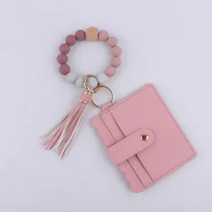 Vista detallada del llavero de pulsera con cuentas de silicona rosa, tarjetero y borla elegante.