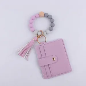Llavero de pulsera con cuentas de silicona, tarjetero de cuero PU y detalle de borla.