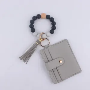 Llavero de pulsera de cuentas de silicona con tarjetero de cuero PU gris y borla colgante.