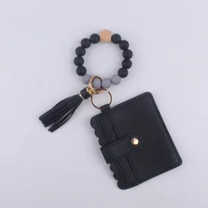 Primer plano del llavero de pulsera de cuentas de silicona con tarjetero de cuero PU y borla.