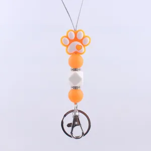 Cute cartoon dog paw silicone keychain with colorful beaded pendant and metal clasp hook.