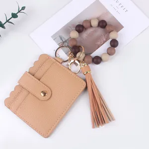 Gros plan détaillé du porte-clés bracelet en perles de silicone avec étui à cartes et pompon.