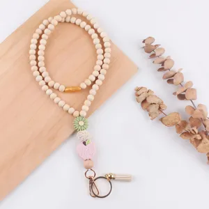Detail shot of wooden bead lanyard featuring a cute pink apple pendant and metal tassel clasp.