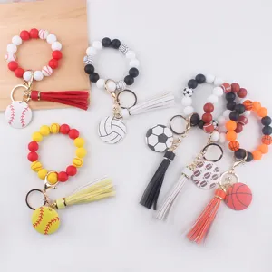 Détail de porte-clés bracelet en perles de silicone avec breloques de sport et pompon.