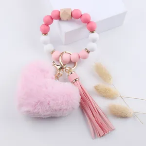 Portachiavi da polso in perle di silicone con ciondolo a cuore in peluche e nappa in pelle PU.